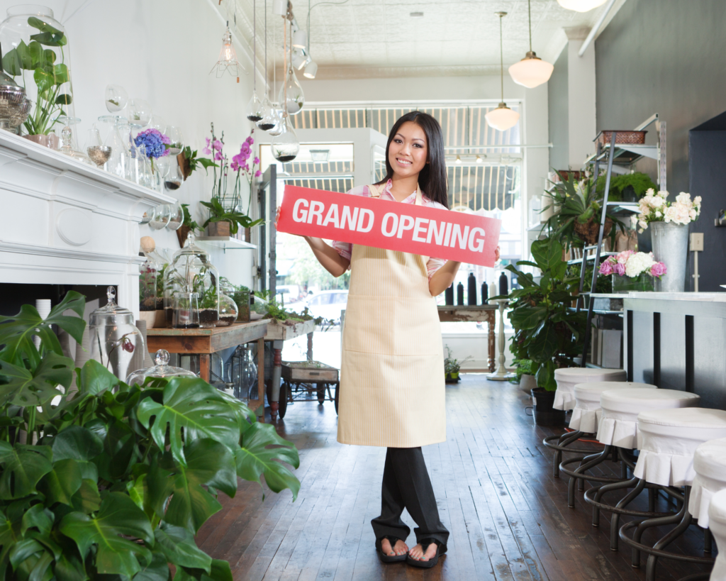 woman holding a sign that says grand opening